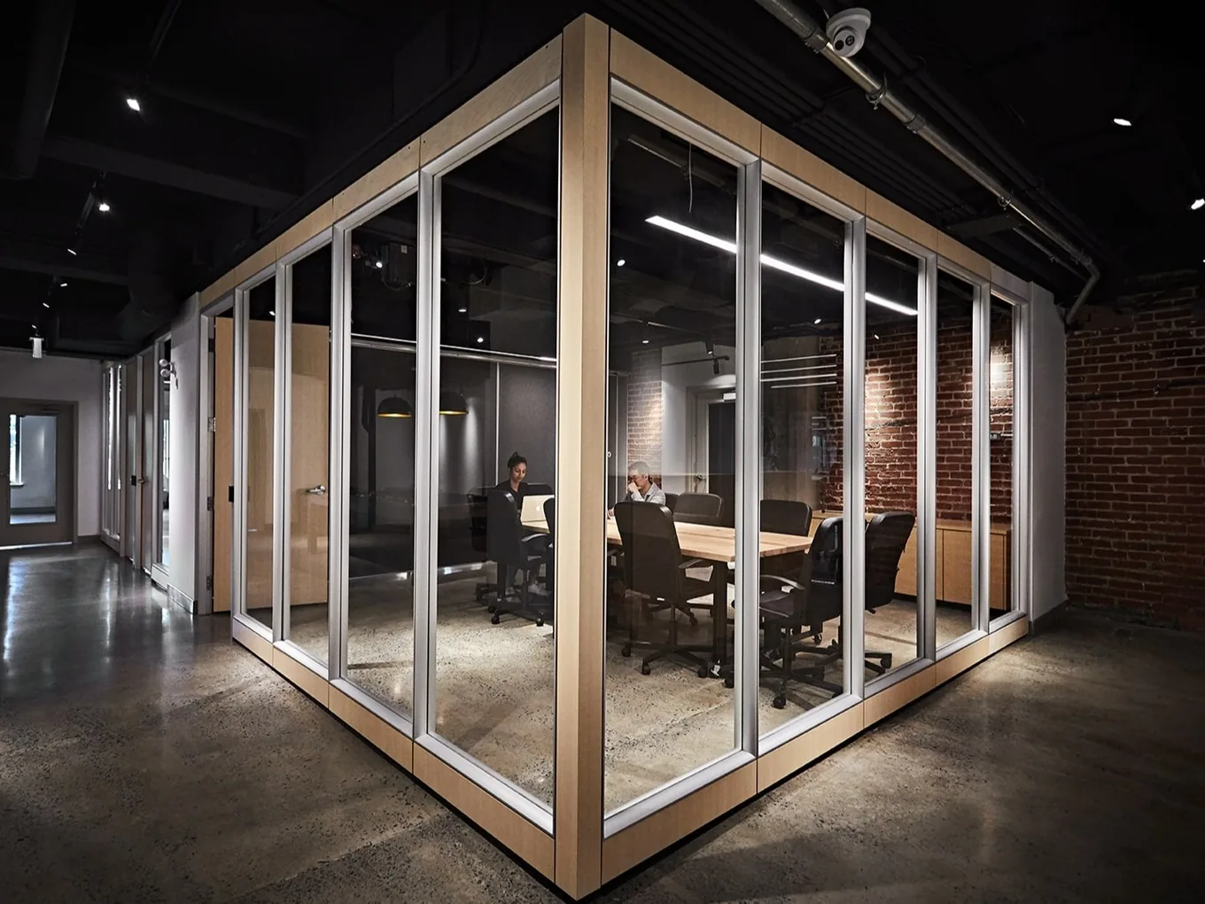 Glass meeting room with exposed brick in the Aloweb workspace